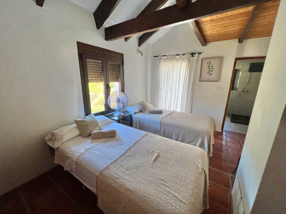 Twin bedroom with white linens and wooden beams