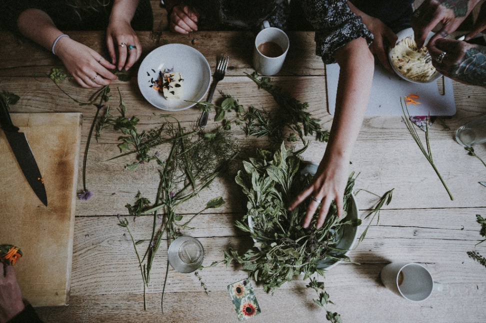 Students sharing a meal around a rustic wooden table with fresh herbs and flowers