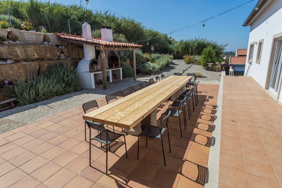 Long outdoor wooden dining table with pizza oven, perfect for group meals